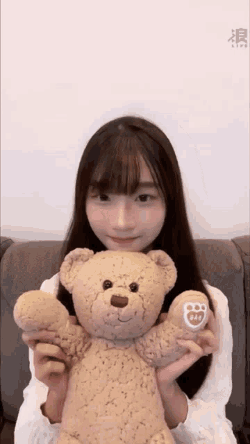 a girl is holding a teddy bear with a sticker on it that says ' fox '