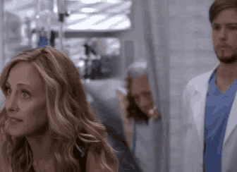 a woman is standing next to a man in a hospital room .
