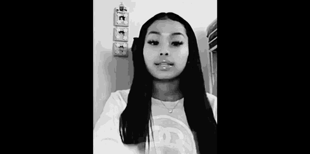 a black and white photo of a girl with long hair and a necklace .