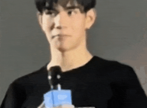 a man in a black shirt is holding a microphone in his hand .