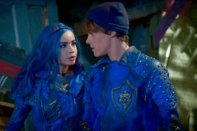a man and a woman are standing next to each other and the woman has blue hair