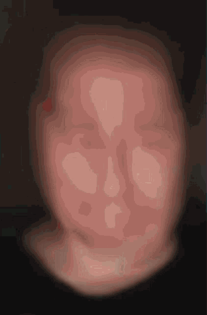 a blurred image of a person 's face with a red spot on the forehead