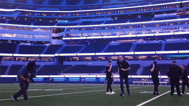 a group of people are standing on a football field in front of a stadium that says the eagles on it