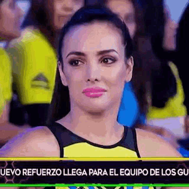 a woman in a yellow and black tank top is sitting in front of a crowd .