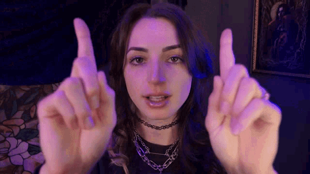 a woman is making a rude gesture with her hands while wearing a choker .