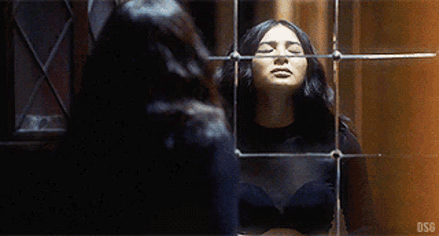 a woman is standing in front of a mirror looking at her reflection .