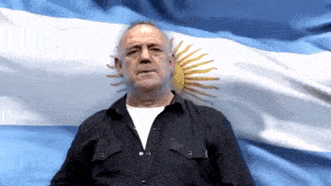 a man in a black shirt is standing in front of a argentina flag