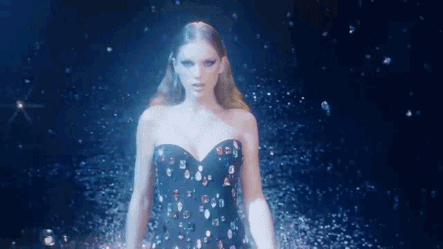 a woman in a black dress with rhinestones on it is surrounded by bubbles .