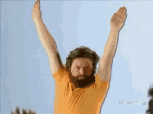 a man with a beard is jumping in the air with his arms in the air .