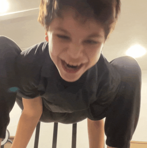 a young boy is doing a handstand with his mouth open