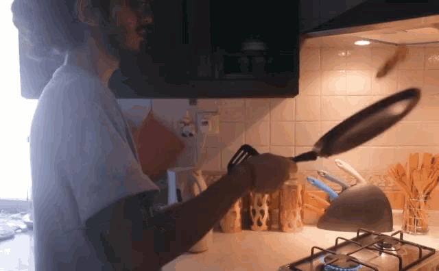 a man is cooking in a kitchen with a frying pan and spatula
