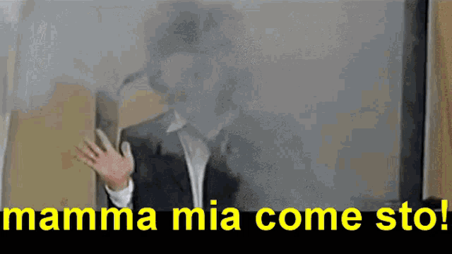 a man in a suit is behind a glass with the words mamma mia come sto in yellow