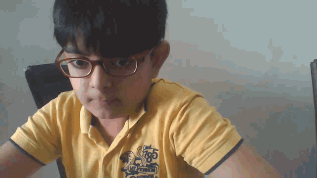 a young boy wearing glasses and a yellow shirt with the word rugby on it