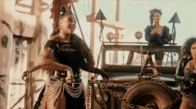 a woman in a black dress is standing next to a jeep with chains around it