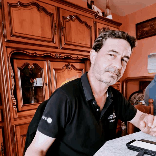 a man sitting at a table wearing a black shirt that says ' santander ' on it