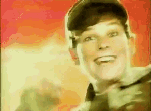 a man wearing a hat and bow tie is smiling while holding a gun .