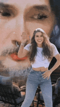 a woman in a white shirt and blue jeans is dancing in front of a painting of a woman .