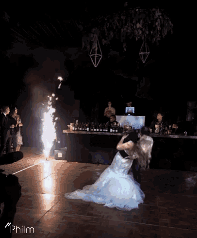 a bride and groom are dancing in front of a fireworks display and the word philm is on the bottom right