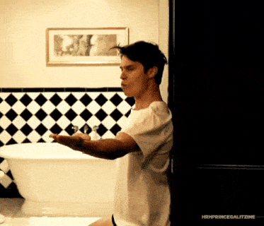 a man in a white shirt is standing in front of a bathtub in a bathroom ..