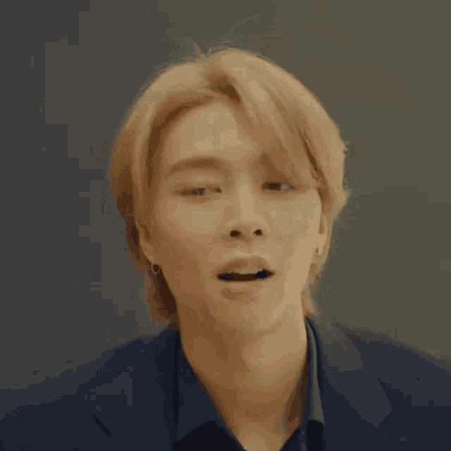 a young man with blonde hair is wearing a black shirt and a black jacket
