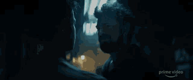 two men are standing next to each other in a dark room .
