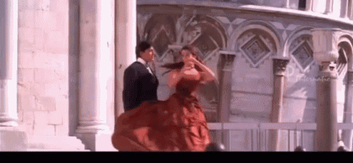 a woman in a red dress is dancing with a man in a tuxedo .