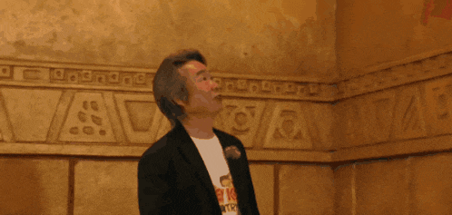 a man wearing a t-shirt with a picture of a man on it looks up at something