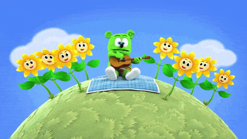 a green gummy bear is sitting on a blanket playing a guitar