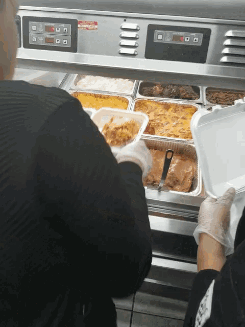 a person is taking a tray of food from a display case that has a digital display that says ' temp '