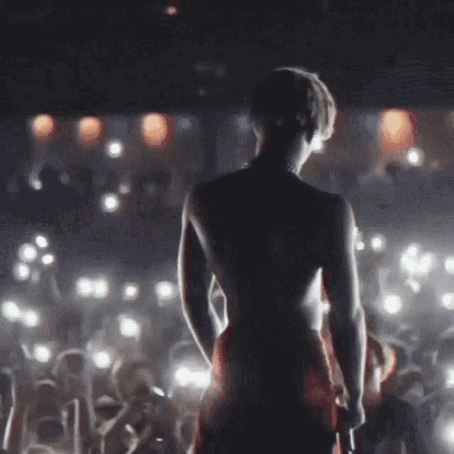 a woman in a red dress is standing on a stage in front of a crowd of people .