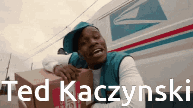 a man is holding a cardboard box with the name ted kaczinski on it