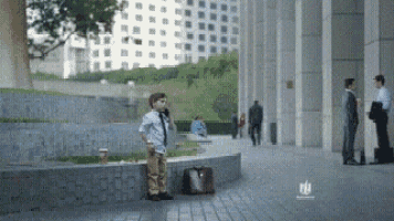 a young boy talking on a cell phone in front of a building with the word nbc on the bottom