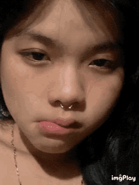 a close up of a woman 's face with a nose ring and a necklace