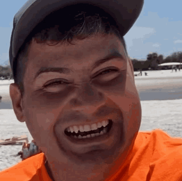 a man wearing a hat and an orange shirt is smiling