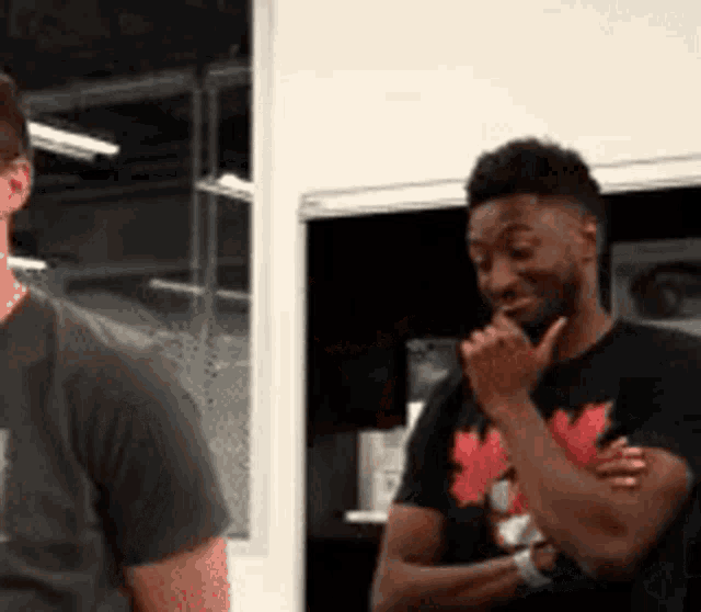 a man wearing a black shirt with a maple leaf on it is laughing