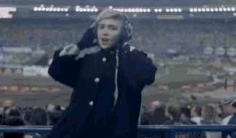a man wearing headphones is standing in front of a crowd of people at a stadium .
