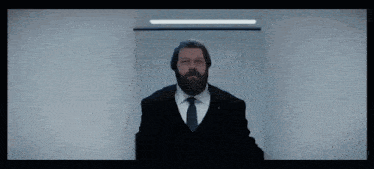 a man with a beard wearing a black suit and tie