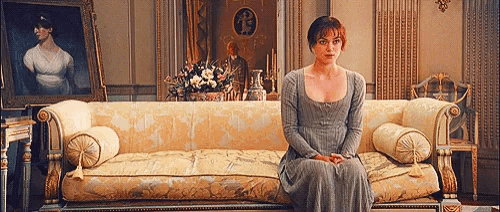 a woman in a dress is sitting on a couch in front of a painting
