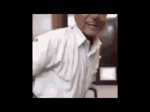 a man in a white shirt is standing in front of a window .