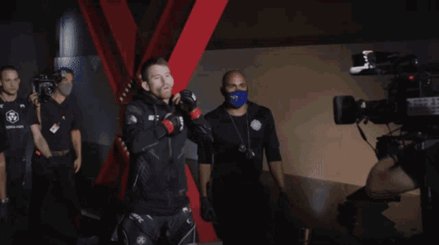 a man in a ufc jacket stands in front of cameras