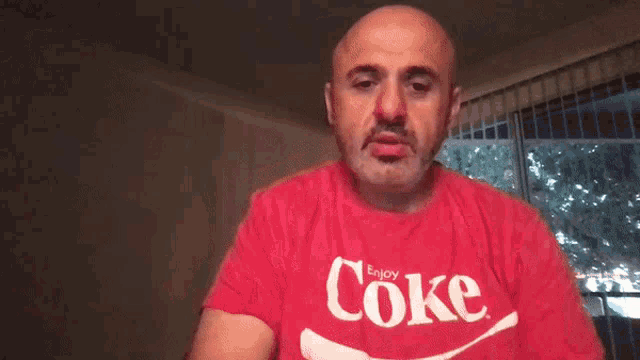 a man wearing a red shirt that says coke
