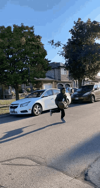 a person running down a street with a white car parked behind them