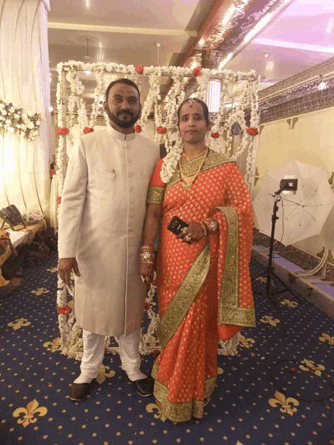 a bride and groom pose for a picture in front of a floral display