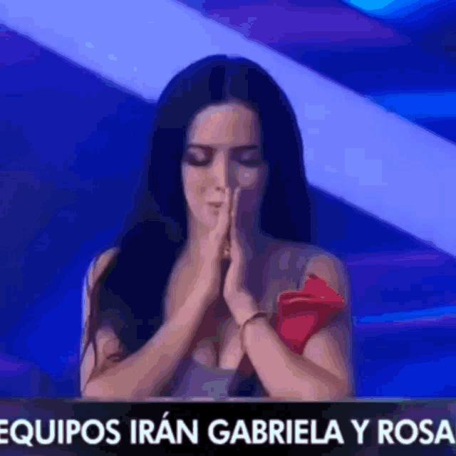 a woman is praying in front of a sign that says " equipos iran gabriela y rosa "