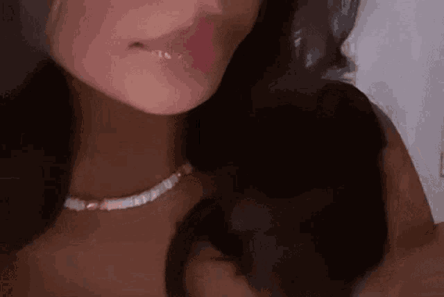 a close up of a woman wearing a necklace and holding her hair .