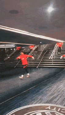 a man in a red shirt is running down stairs in a gym