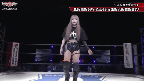 a woman stands in a wrestling ring with a sign that says stardom