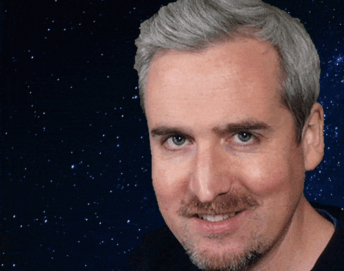 a man with gray hair and a beard smiles in front of a starry background