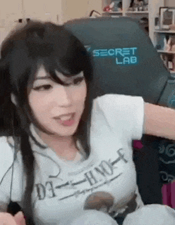 a woman is sitting in a chair with her arm outstretched while wearing a white t-shirt .