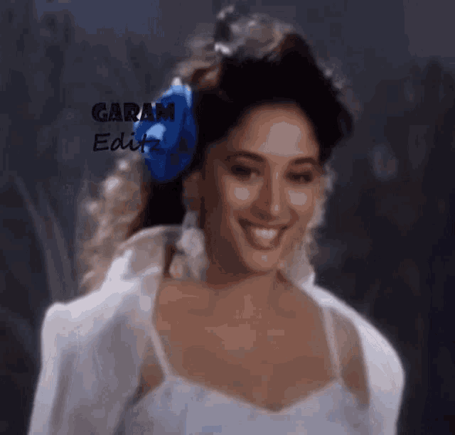 a woman in a white dress with a blue bow in her hair is smiling with the words garam edit on the bottom